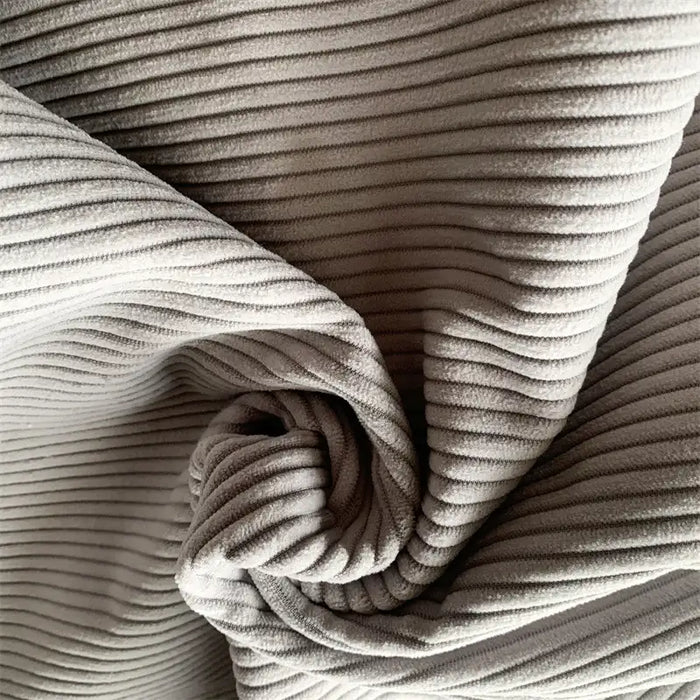 Close-up of Longan Craft 4.5 Wale Polyester Corduroy Fabric By The Yard shows light grey wide wale ridges and folds, highlighting the durable, textured look of this solid color material—ideal for making pants.