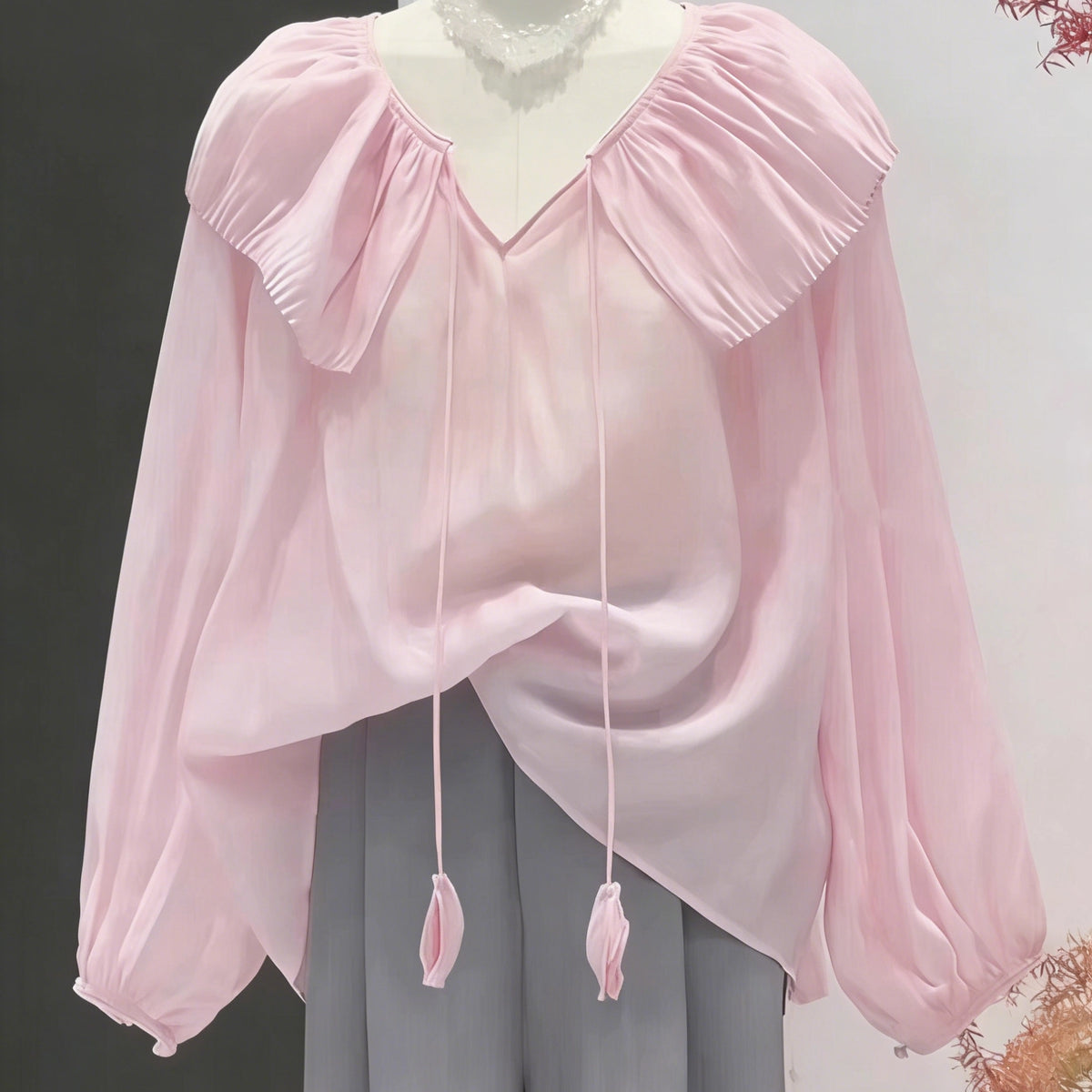 The mannequin features a chic look made with Longan Craft's Ruffle Collar Long-Sleeved Blouse Free Sewing Pattern, paired with loose gray pants. Download the free PDF pattern to recreate this stylish outfit yourself.