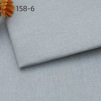A close-up of Longan Craft’s Faux Linen Upholstery Fabric By The Yard shows two overlapping pieces in light gray with a woven texture. An orange flower appears at the top left, along with the code 158-6.