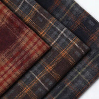 Three swatches of Semi Worsted Plaid Wool Fabric By The Yard in dark plaid patterns of red, gray, and brown, suitable as fabric for coats.