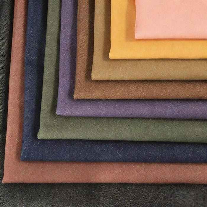 A fan-shaped stack of Longan Craft 9.5oz Stretch Denim Fabric By The Yard showcases solid colors like brown, purple, green, orange, and pink—ideal cotton denim textile for jeans.