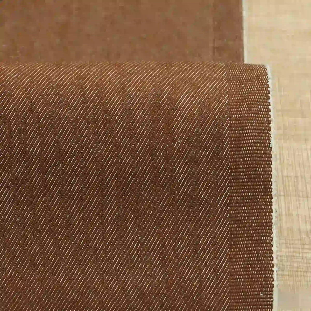 A close-up of Longan Craft 9.5oz Stretch Denim Fabric By The Yard shows its solid color cotton material with fine diagonal weave lines and a clean, even edge—ideal textile for making jeans.