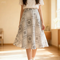 A person wears a white short-sleeve top and a black-and-white patterned skirt made with the Longan Craft Women A-line Midi Skirt Sewing Pattern (Free PDF Skirt Pattern Download), standing indoors on a sunlit wooden floor. Face not visible.