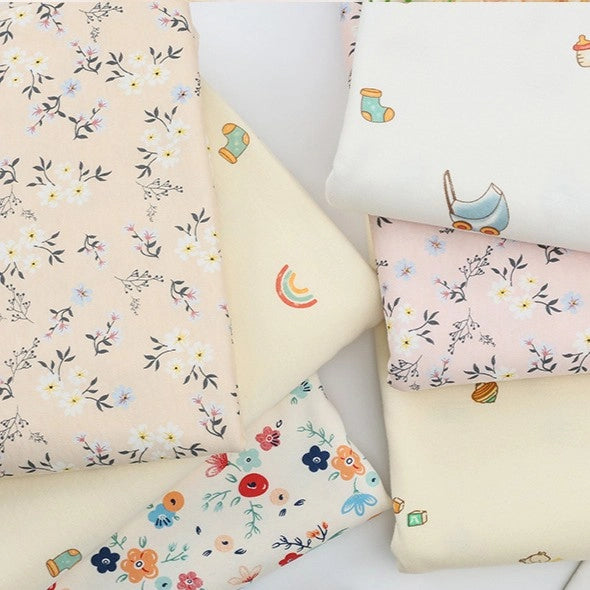 A stack of Longan Craft Animal and Botanical Printed Jersey Fabric by the yard—heavyweight cotton jersey with a variety of pastel patterns, including florals, animals, and playful motifs.