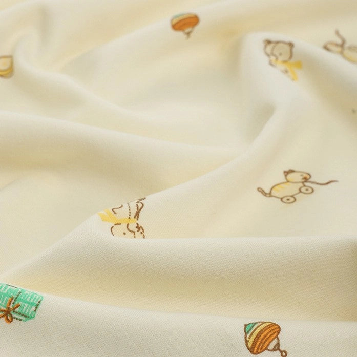 Longan Craft’s Animal and Botanical Printed Jersey Fabric is a cream-colored, heavy-weight 100% cotton sweatshirt jersey by the yard, with playful prints of toys, animals, and gifts across its soft surface.