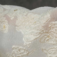 Close-up of Apricot Rose Embossed Organza Fabric by Longan Craft features 3D floral jacquard with lustrous embroidery, creating a textured and elegant look—ideal soft organza for summer dresses. Background is blurred to highlight the intricate design.