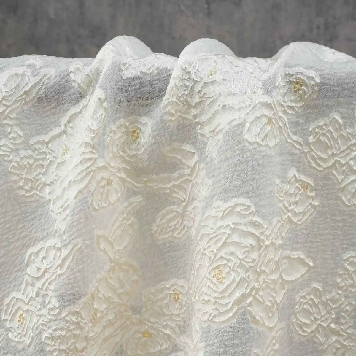 A close-up of Longan Craft's Apricot Rose Embossed Organza Fabric showcases its 3D floral jacquard pattern and soft folds, draped elegantly with subtle texture against a neutral gray background—ideal for summer dresses by the yard.
