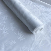 A roll of Longan Craft Bamboo Jacquard Mulberry Silk Fabric is partially unrolled, displaying its subtle, glossy pattern and delicate design, perfect as colorful rayon silk lining fabric by the yard.