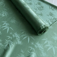 A roll of Longan Craft's Bamboo Jacquard Mulberry Silk Fabric, a colorful rayon silk with a subtle glossy pattern, is unrolled across a flat surface, perfect for cozy silk linings by the yard.