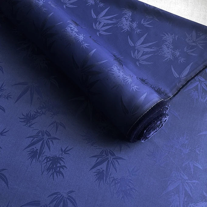 A roll of Longan Craft Bamboo Jacquard Mulberry Silk Fabric is partially unrolled, revealing a smooth, colorful rayon silk material with a subtle glossy pattern that reflects light. Perfect as a cozy silk lining fabric.