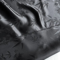 The Bamboo Jacquard Mulberry Silk Fabric by Longan Craft is a colorful rayon silk fabric with a smooth, glossy bamboo leaf pattern and a visible diagonal stitched seam. Slightly wrinkled, it's ideal for cozy silk lining.