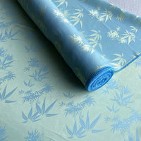 A roll of Longan Craft Bamboo Jacquard Mulberry Silk Fabric, featuring a colorful botanical jacquard pattern, partially unrolled on a flat surface—ideal as cozy silk lining fabric by the yard.