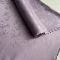 A close-up of Longan Craft’s Bamboo Jacquard Mulberry Silk Fabric By The Yard, a lustrous, subtly patterned colorful rayon silk fabric partially rolled out on a flat surface.