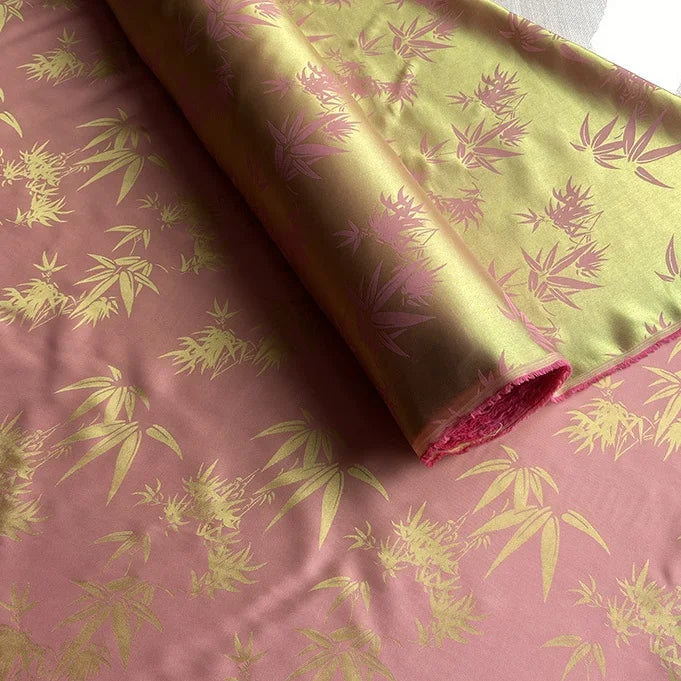 A close-up of Longan Craft’s Bamboo Jacquard Mulberry Silk Fabric by the yard shows an intricate, shiny pink and gold pattern—ideal as colorful rayon silk fabric or cozy silk lining.