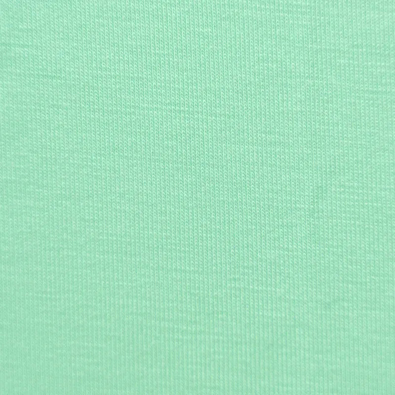 Close-up of Longan Craft Bamboo Jersey Fabric By The Yard shows a soft, light green plain color with fine vertical knit lines—ideal for eco-friendly loungewear and baby clothing. This single elastane jersey material is soft, even, and smooth to the touch.
