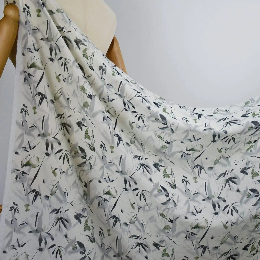 Longan Craft's Bamboo Printed Nylon Viscose Fabric By The Yard features a delicate gray and green leafy chinoiserie print, draped over a mannequin to highlight its lightweight, airy texture—perfect for premium dressmaking projects.