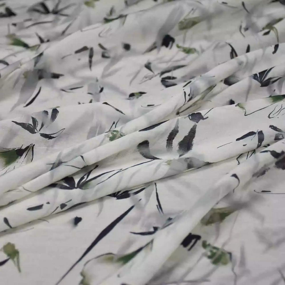 A close-up of Longan Craft’s Bamboo Printed Nylon Viscose Fabric, a lightweight, eco-friendly viscose material with a soft abstract floral print in green, black, and grey, draped in gentle folds – ideal for premium dressmaking.