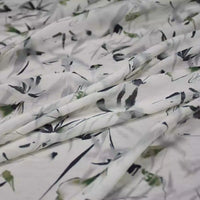 A close-up of Longan Craft’s Bamboo Printed Nylon Viscose Fabric, a lightweight, eco-friendly viscose material with a soft abstract floral print in green, black, and grey, draped in gentle folds – ideal for premium dressmaking.