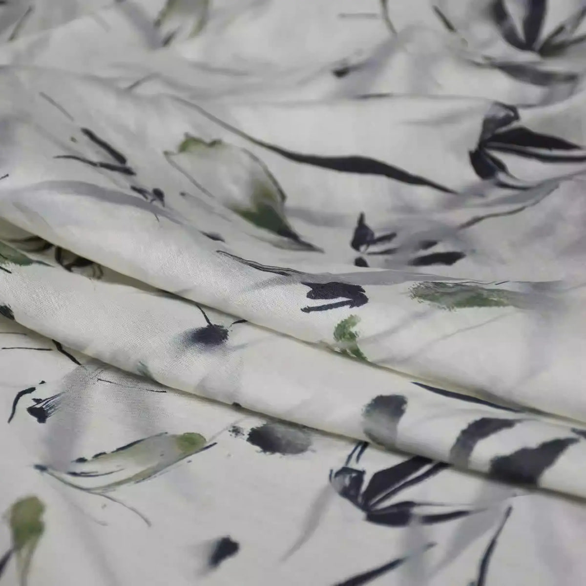 Close-up of Longan Craft's Bamboo Printed Nylon Viscose Fabric By The Yard, featuring a chinoiserie-inspired abstract floral print in green, black, and gray on lightweight eco-friendly viscose, softly draped with gentle folds.