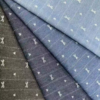 Four pieces of Bow Heart Jacquard Denim Fabric by Longan Craft in blue and black shades, featuring small white scissors and dotted line square patterns. The striped cotton-polyester blend denim is arranged overlapping diagonally.