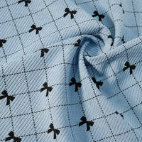 The Light Blue Bow Plaid Print Corduroy Fabric by Longan craft features a classic black grid pattern with small black bows at each intersection, shown here loosely gathered in the center. This heavyweight, soft, and durable checked corduroy material is ideal for clothing and is available by the yard.