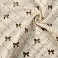 Showcasing the distinctive charm of Longan craft’s Bow Plaid Print Corduroy Fabric By The Yard, this heavyweight checked corduroy features a cream-colored ribbed texture adorned with a grid pattern and delicate brown bows at each intersection. Slightly twisted in the center, the soft and durable material beautifully highlights its rich texture and flexibility—making it an ideal choice for corduroy clothing projects.
