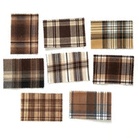 Eight rectangular fabric swatches from Longan Craft’s Brown Plaid Cotton Flannel Fabric by the yard—featuring classic retro plaid patterns in shades of brown, cream, and blue—are arranged on a white background. Each lightweight polyester brushed flannel sample has zigzag-cut edges, ideal for those seeking high-quality fabric for casual pants or other sewing projects.