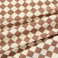 Close-up of Longan Craft's Checkered Corduroy Fabric By The Yard shows its soft, durable printed polyester in a brown and beige checkerboard. Ribbed texture and visible folds create depth, highlighting this unique fabric for apparel.
