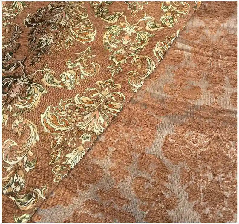 A close-up of Longan Craft's Chenille Damask Fabric by the Yard shows its ornate gold and beige floral jacquard pattern on brown, with the damask upholstery fabric partially folded to reveal its elegant design from various angles.