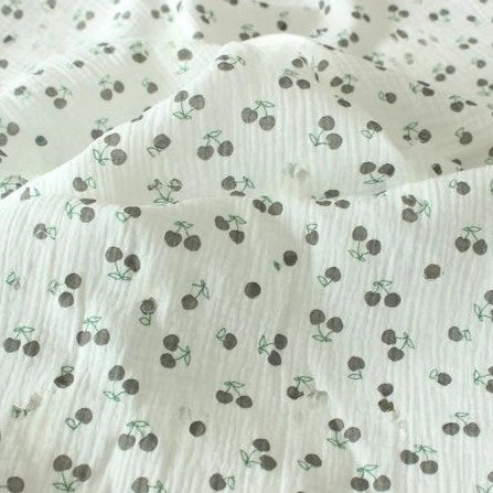 Longon Craft's Cherry Print Double Gauze Fabric by the Yard features a soft, crinkled white cotton with small black cherries and green stems—ideal muslin fabric for sewing children's clothes and projects.