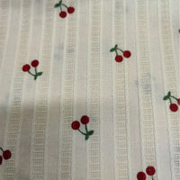 Longan Craft's Cherry Printed Textured Dobby Fabric features colorful cotton stripes and embroidered red cherries with green stems on cozy dobby material—perfect for apparel and sold by the yard.