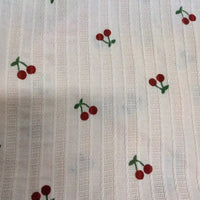 Longan Craft’s Cherry Printed Textured Dobby Fabric by the Yard features playful red cherries and green stems on white vertical striped cotton, perfect for cozy apparel and crafts.