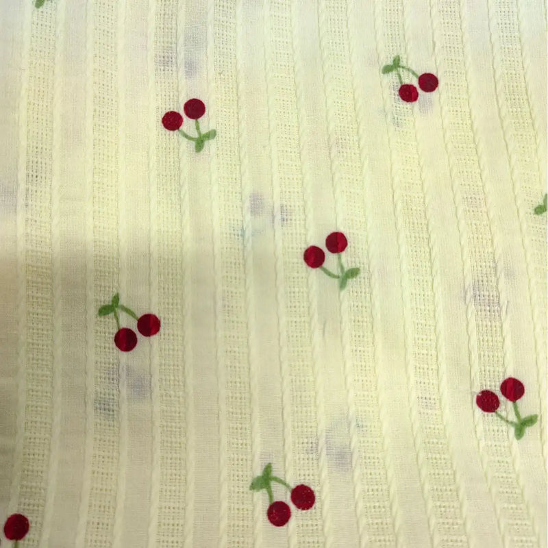 Cherry Printed Textured Dobby Fabric by Longan Craft features cozy cream cotton with vertical stripes and small red cherry prints with green stems—perfect for apparel. Available by the yard.