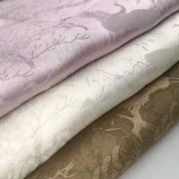 Three folded pieces of Longan Craft Chinoiserie Polyester Viscose Fabric in pastel pink, off-white, and taupe, each with a subtle shiny botanical jacquard pattern. Ideal for curtains and inspired by Chinoiserie designs.