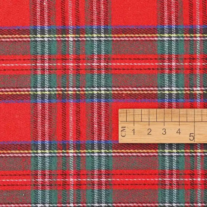 A wooden ruler marked in centimeters rests on the Christmas Plaid Sueded Flannel Fabric By The Yard from Longan Craft, highlighting the bold red, green, and white checked holiday pattern. The scale demonstrates the detailed weave and vibrant colors of this brushed flannel textile—ideal for classic dresses or festive sewing projects.