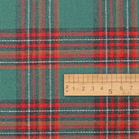 A Longan Craft wooden ruler placed atop Christmas Plaid Sueded Flannel Fabric by the yard showcases the festive green and red checked pattern—ideal for classic holiday dressmaking and seasonal sewing projects.