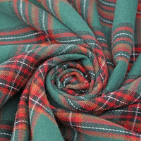 Close-up of green, red, white, and black plaid fabric from Longan Craft’s Christmas Plaid Sueded Flannel Fabric By The Yard twisted into a spiral, highlighting its soft, sueded texture and intricate woven design—ideal for holiday sewing projects with this checked holiday flannel textile perfect for classic dresses and festive décor.