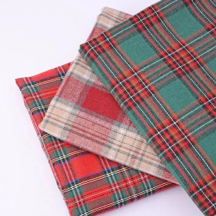 Three folded pieces of Longan Craft Christmas Plaid Sueded Flannel Fabric by the Yard, featuring red, green, and beige checked holiday patterns, are stacked on a white background. This soft sueded flannel sewing material is perfect for festive projects and classic dresses, adding warmth and seasonal charm to your creations.