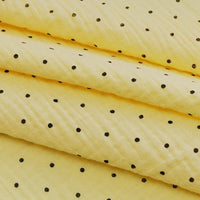 Close-up of Longan Craft’s Classic Small Polka Dot Gauze Fabric: 100% cotton double gauze, yellow with small black polka dots—ideal for baby clothing and pajamas, sold by the yard.