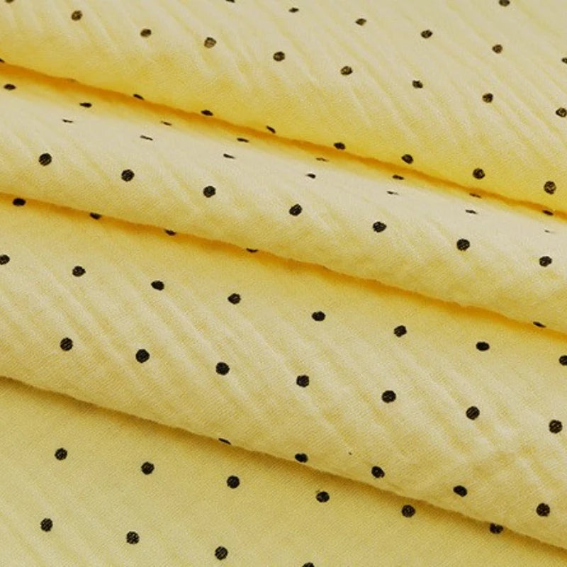 Close-up of Longan Craft’s Classic Small Polka Dot Gauze Fabric: 100% cotton double gauze, yellow with small black polka dots—ideal for baby clothing and pajamas, sold by the yard.