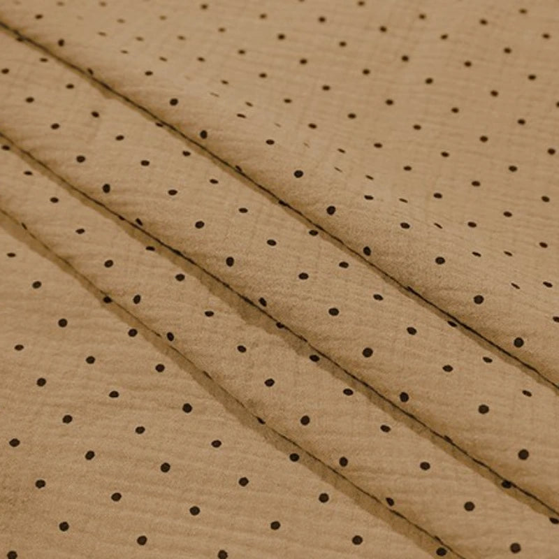 Longan Craft’s Classic Small Polka Dot Gauze Fabric by the yard is 100% cotton double gauze with brown crinkled texture and black polka dots, perfect for baby clothing or pajamas. Shown in shallow folds.