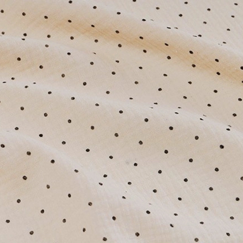 A close-up of Longan Craft's Classic Small Polka Dot Gauze Fabric shows soft beige 100% cotton double gauze with evenly spaced small black dots, ideal for baby clothing or pajamas, available by the yard.