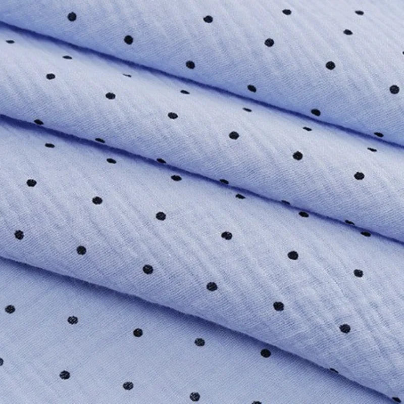 The Classic Small Polka Dot Gauze Fabric by Longan Craft is 100% cotton double gauze with small black polka dots on light blue. Shown folded, it's ideal for baby clothing, pajamas, or delicate projects. Sold by the yard.