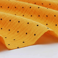 Close-up of Longan Craft’s Classic Small Polka Dot Gauze Fabric by the yard—100% cotton double gauze with a textured yellow surface and evenly spaced small black polka dots, perfect for baby clothing and pajamas.
