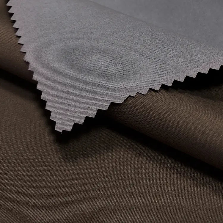 A detailed view of Longan Craft’s Coated Waterproof Peachskin Fabric By The Yard—two overlapping microfiber polyester swatches, dark brown and gray, with the gray peachskin showing a zigzag-cut edge ideal for cozy jacket making.