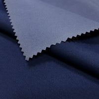 A close-up of two overlapping pieces of Longan Craft Coated Waterproof Peachskin Fabric by the Yard, featuring dark blue microfiber polyester with a zigzag-cut edge and cozy texture—ideal for jacket making and rainwear.