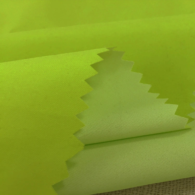 Close-up of folded neon yellow Longan Craft Coated Waterproof Peachskin Fabric By The Yard, a microfiber polyester material with zigzag edges, highlighting its cozy peachskin texture and multiple layers for jacket making.