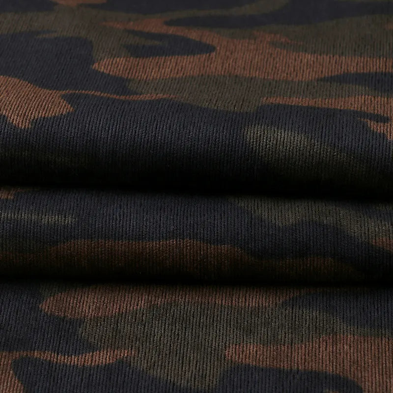 A close-up of Longan Craft's Colorful Camouflage Corduroy Fabric by the yard displays its quality weave and distinct dark green and brown camouflage pattern, ideal for clothing.