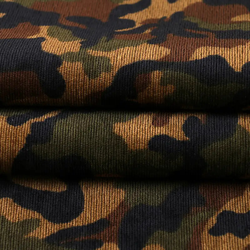 Close-up of Longan Craft's Colorful Camouflage Corduroy Fabric By The Yard, showing green, brown, tan, and black print with visible texture and horizontal ribbing—ideal quality material for clothing.