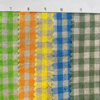 Five strips of Longan Craft’s Colorful Checkered Linen Fabric By The Yard—100% washed linen gingham in green, orange, yellow, blue, and gray—are displayed with a ruler on top numbered 7 to 11 and pinked edges between each color.